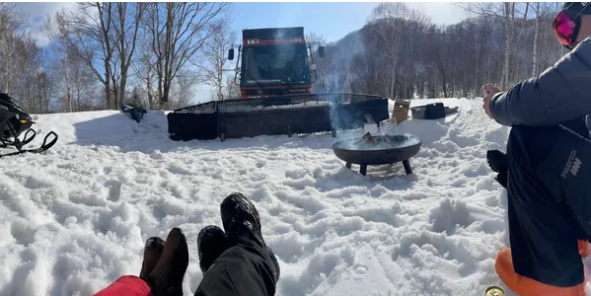 Guests warming up at a campfire during a tour break