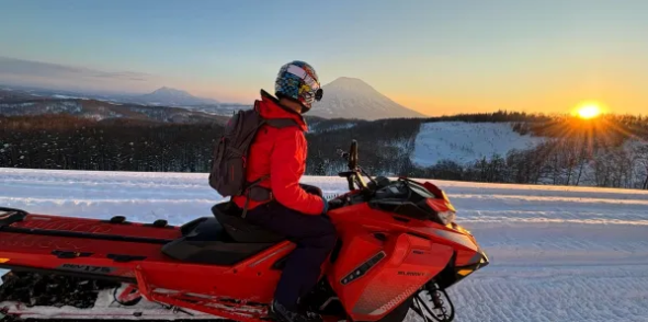 Rider on a snowmobile at sunset with Mt Yotei in the distance