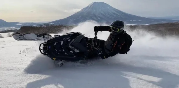 Rider kicking up powder with Mt Yotei in the background