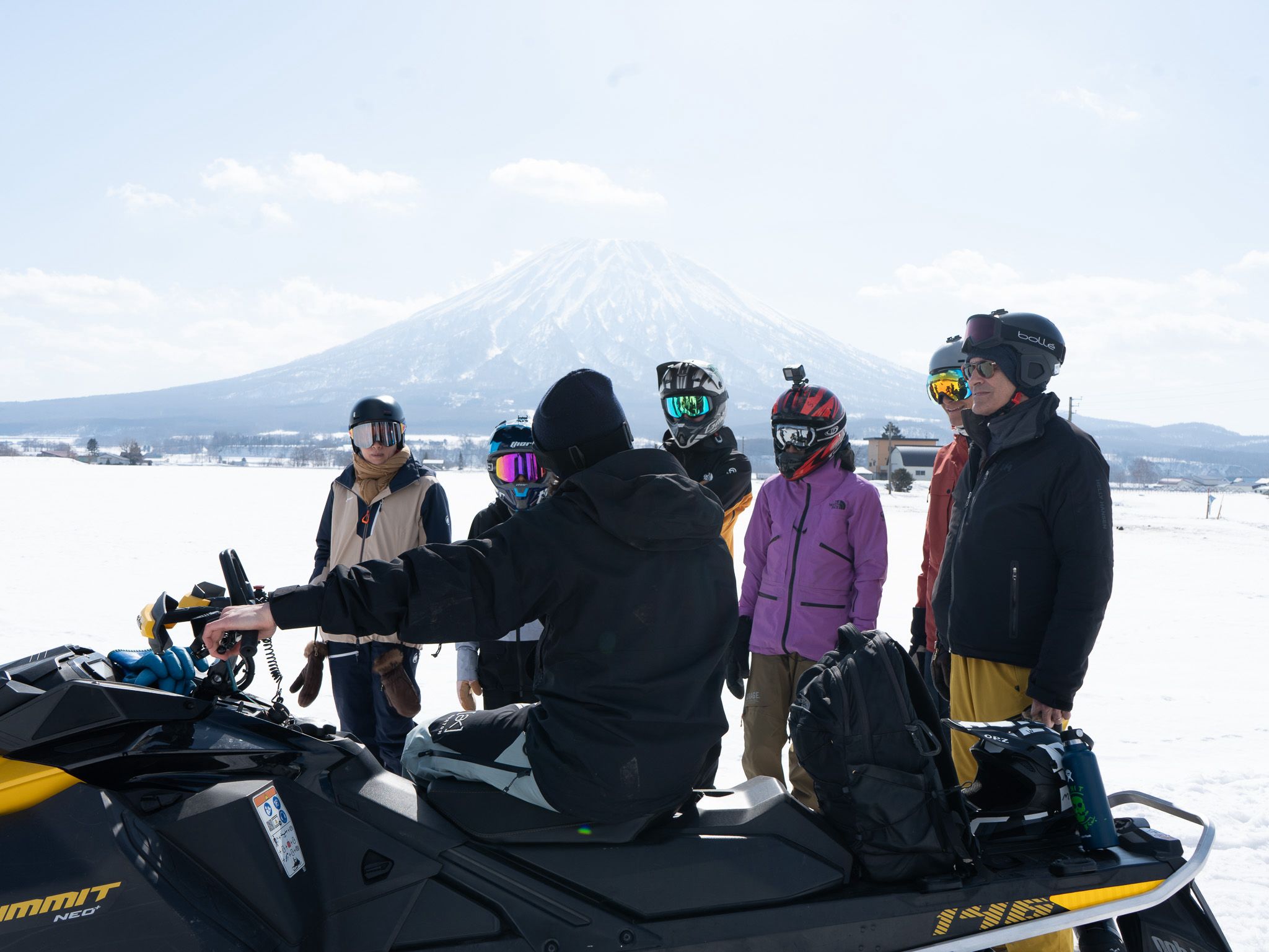 Guide giving a safety briefing to a group of riders with Mt Yotei behind them